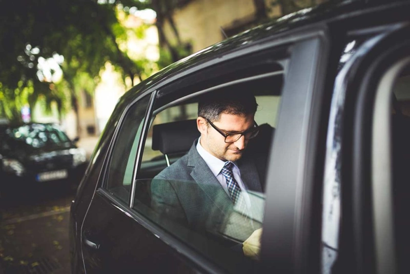 Luxury corporate transportation Chicago with a professional chauffeur and premium executive vehicle outside a modern office building.