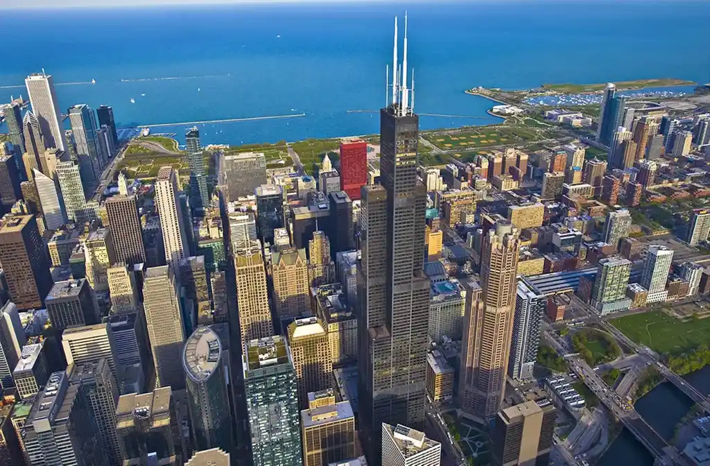 Luxury limo service to Willis Tower featuring a sleek black stretch limousine parked near the iconic skyscraper, showcasing premium transportation in downtown Chicago.