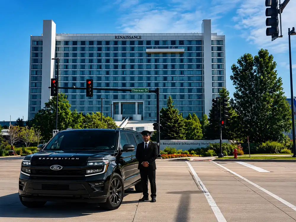 Professional chauffeur standing beside a black Ford Expedition luxury SUV outside the Renaissance Schaumburg Hotel, providing premium chauffeur and executive transportation service.